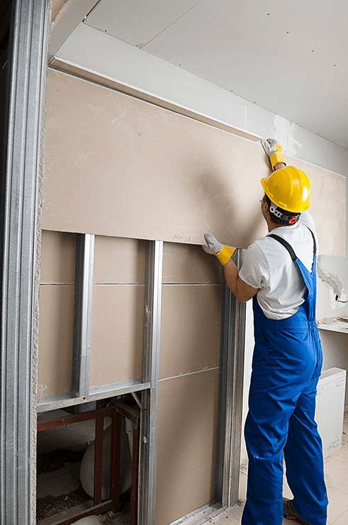 Ein Mann befestigt Gipskartonplatten an der Unterkonstruktion aus Metall