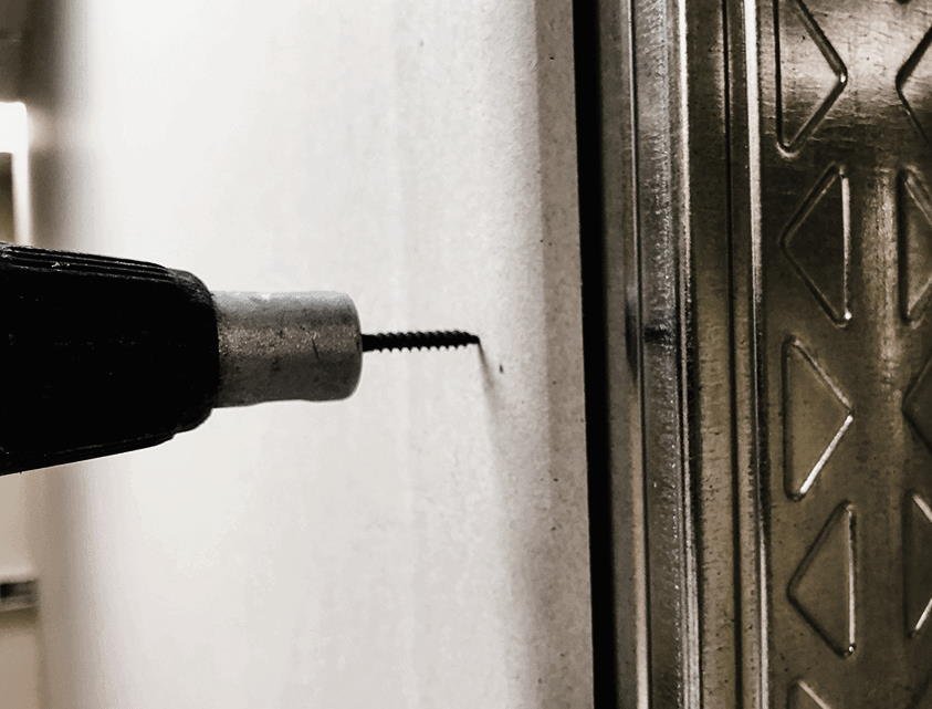 Eine Gipskatonplatte wird an ihre Halterung aus Metall geschraubt